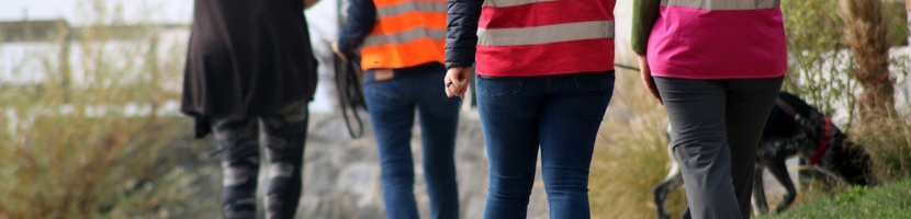 Frauen mit Rettungsweste und Hund beim Suchen einer Person